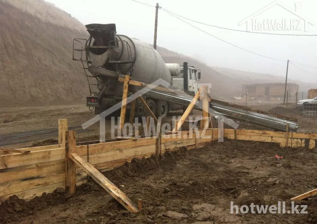 Заливка бетона в опалубку фундамента дома «Б-205»: автомиксер подаёт смесь по лотку