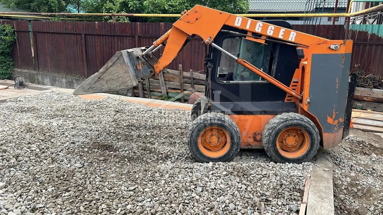 Мини-погрузчик разравнивает гравийную подушку фундамента дома «Д-132»