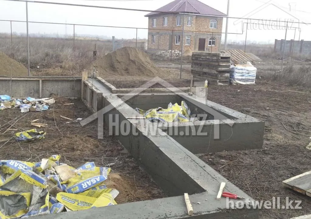 Залитый ленточный фундамент дома «К-148Б» в опалубке, рядом песок и цемент
