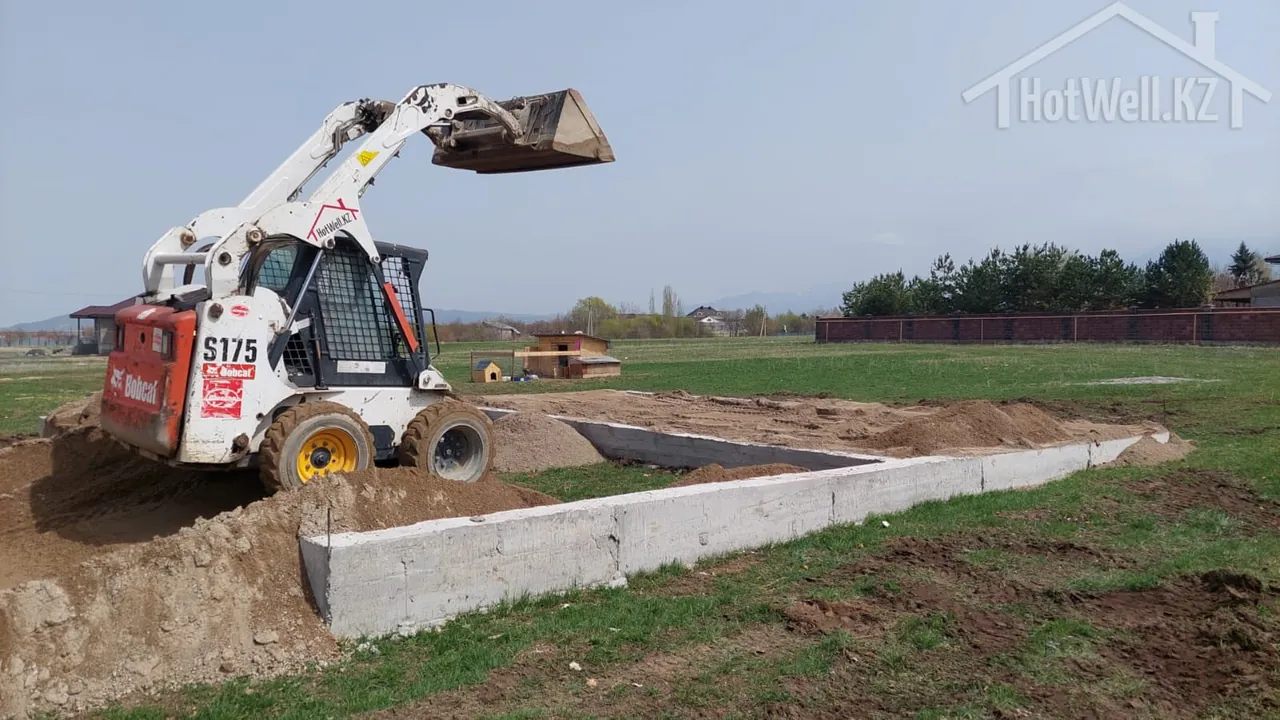 Погрузчик Bobcat S175 разравнивает песчаную засыпку по ленточному фундаменту