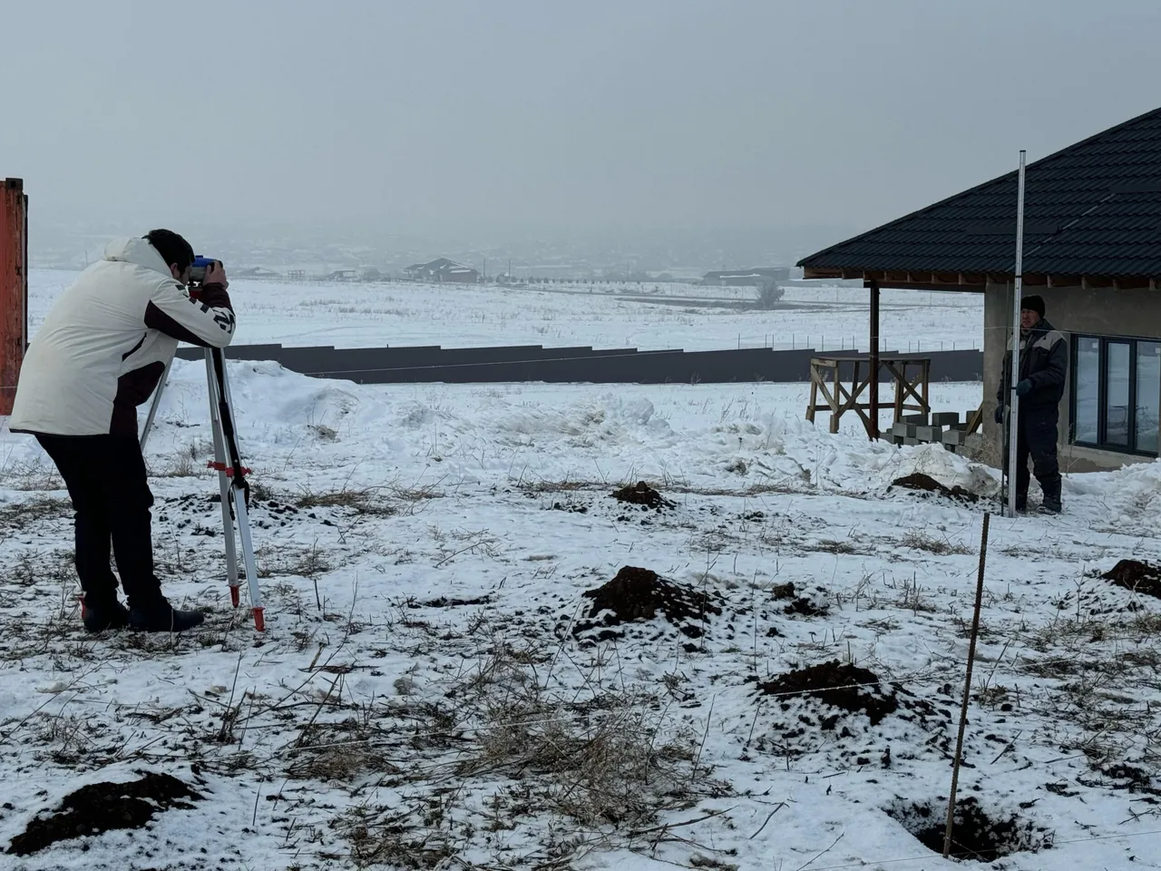 Разметка пятна застройки дома «А-190»: замеры нивелиром и рейкой на заснеженном участке