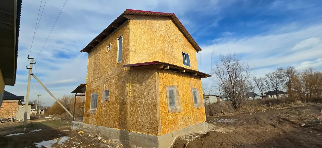 Коробка дома «М-100» из СИП-панелей под красной кровлей, вид со стороны двора