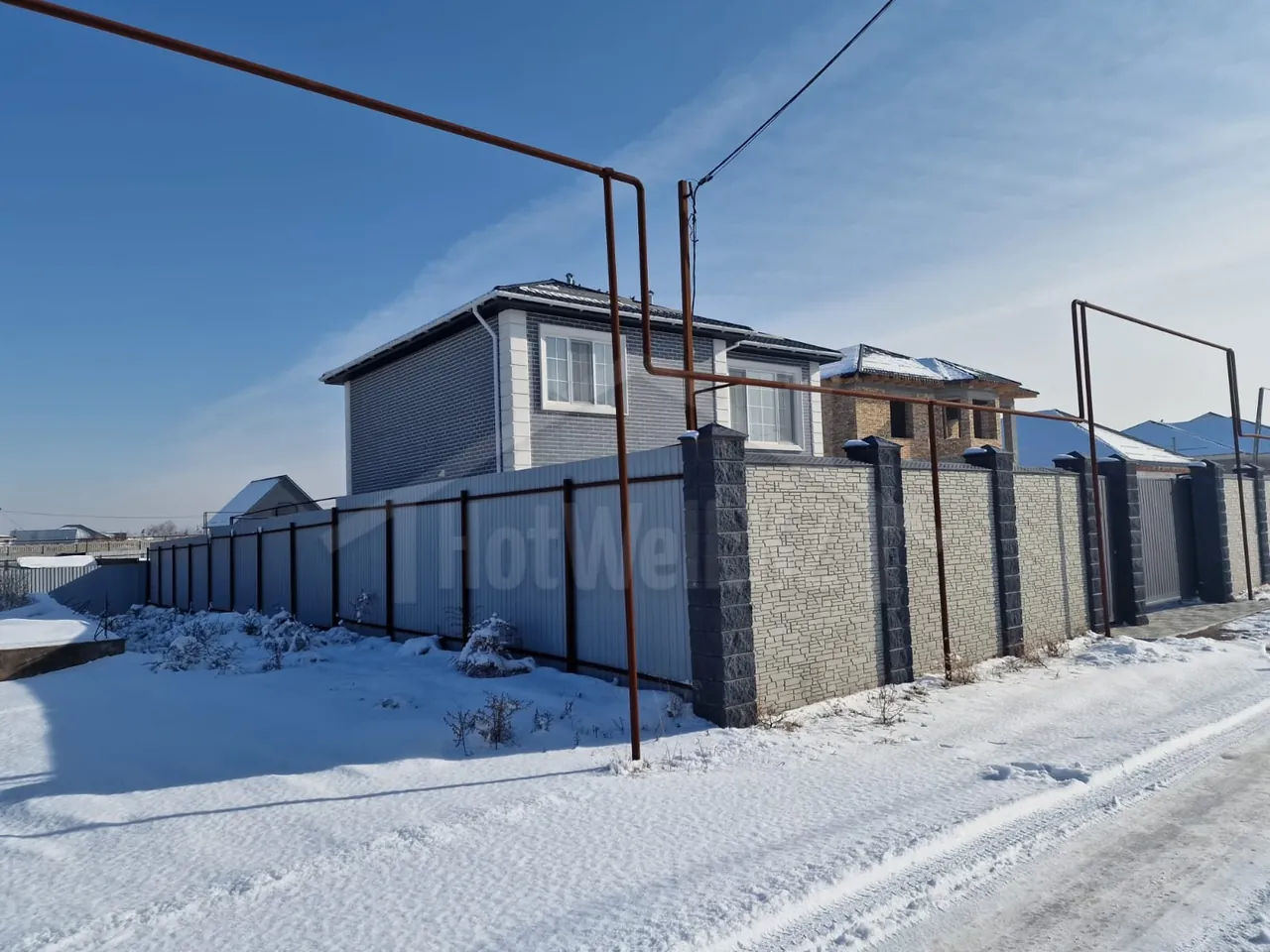 Дом «О-185» за забором из профлиста, вид с заснеженной улицы посёлка
